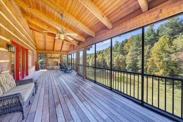 unfurnished sunroom featuring ceiling fan, wood ceiling, and lofted ceiling with beams