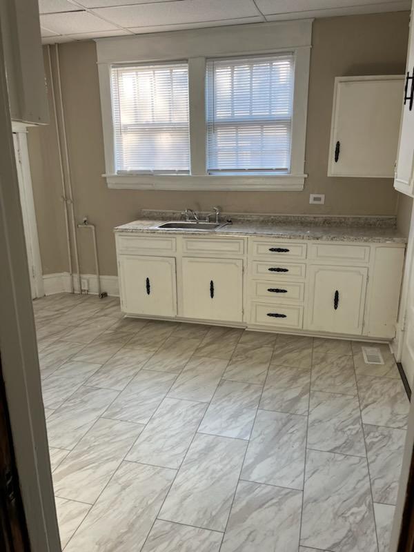 kitchen with white cabinetry, a paneled ceiling, and sink