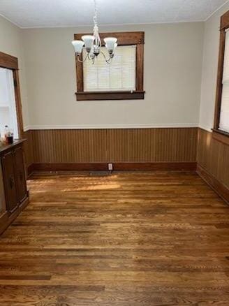 spare room featuring wooden walls, a chandelier, and dark hardwood / wood-style flooring