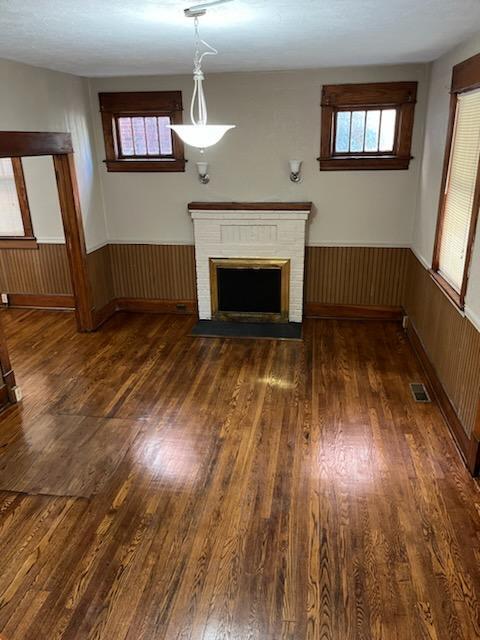 unfurnished living room featuring a fireplace, wood walls, and dark hardwood / wood-style flooring