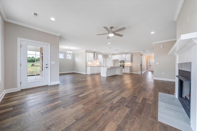 unfurnished living room with dark hardwood / wood-style flooring, ceiling fan with notable chandelier, and ornamental molding