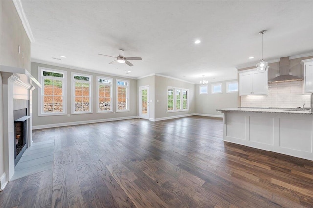 unfurnished living room featuring ceiling fan, ornamental molding, and dark wood-type flooring