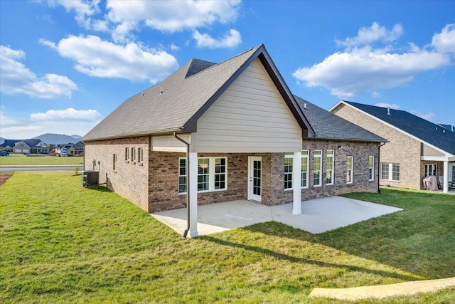 rear view of house with central air condition unit, a lawn, and a patio