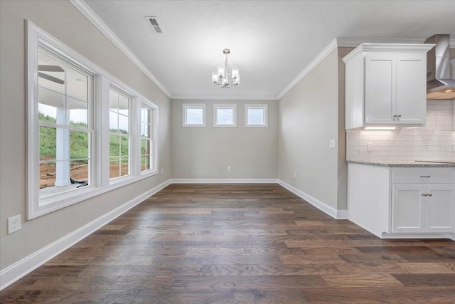 unfurnished dining area featuring dark hardwood / wood-style floors, crown molding, and a notable chandelier