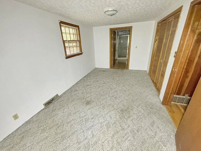 carpeted spare room featuring a textured ceiling