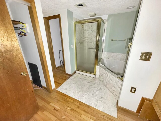 bathroom featuring a textured ceiling, wood-type flooring, and shower with separate bathtub