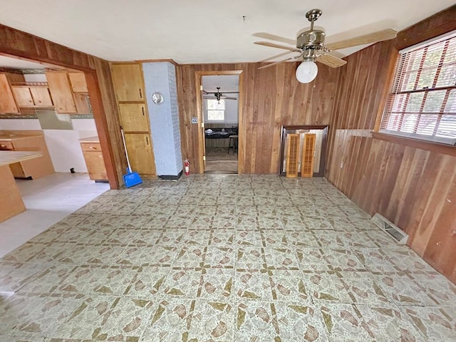 unfurnished dining area featuring ceiling fan, wood walls, and plenty of natural light