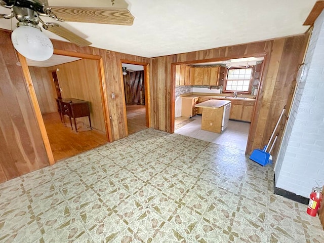 interior space featuring ceiling fan, brick wall, wood walls, and sink