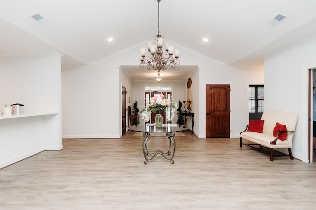 sitting room featuring light wood-type flooring, ornamental molding, vaulted ceiling, and a chandelier