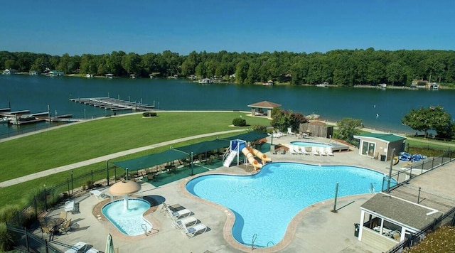 view of pool with a patio, a water view, a hot tub, and a yard