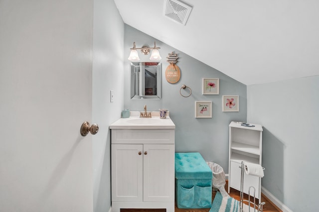 bathroom with lofted ceiling, hardwood / wood-style floors, and vanity