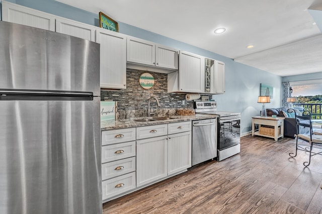 kitchen featuring dark hardwood / wood-style floors, sink, white cabinets, stainless steel appliances, and dark stone countertops