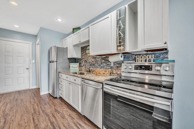 kitchen with light stone counters, sink, white cabinetry, stainless steel appliances, and dark hardwood / wood-style flooring