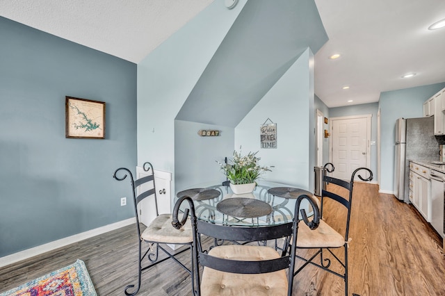 dining space featuring wood-type flooring and vaulted ceiling