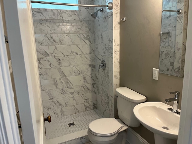 bathroom with tiled shower, toilet, and sink