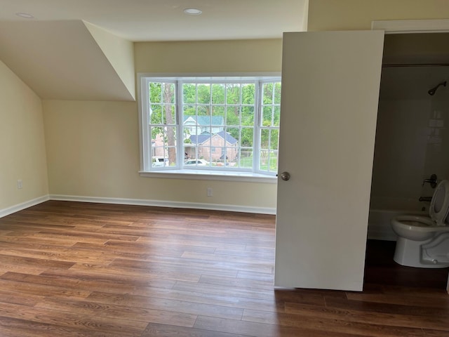 unfurnished bedroom with connected bathroom, a closet, and dark hardwood / wood-style flooring