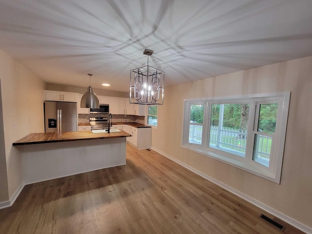 kitchen with pendant lighting, white cabinetry, an inviting chandelier, stainless steel appliances, and wooden counters