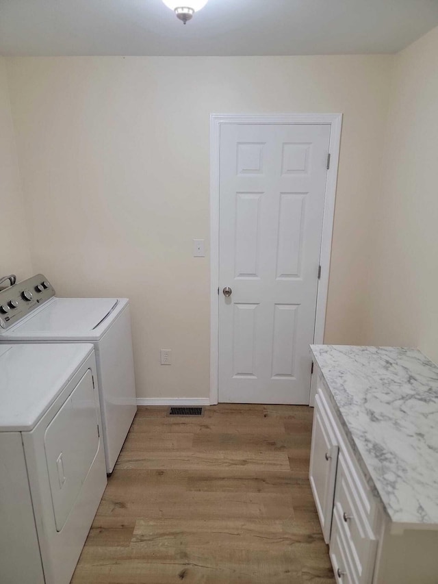 washroom with cabinets, light wood-type flooring, and separate washer and dryer