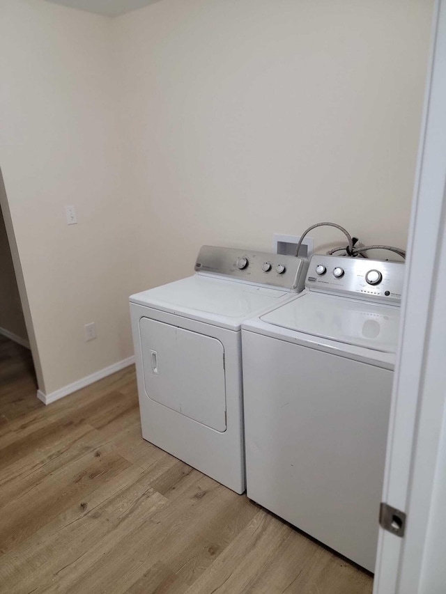 clothes washing area featuring light wood-type flooring and washer and clothes dryer