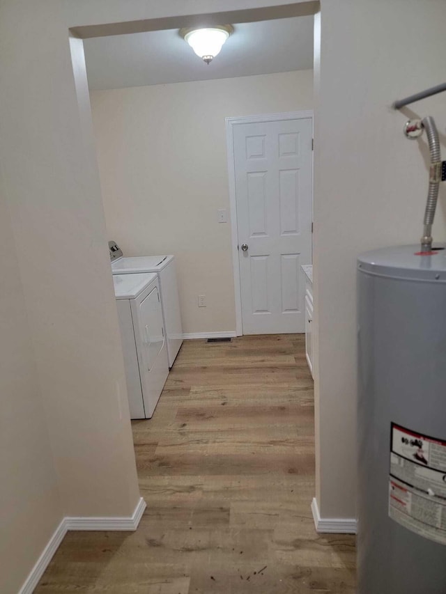 laundry room with electric water heater, light wood-type flooring, and washing machine and clothes dryer