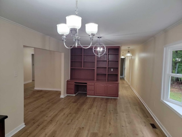 unfurnished living room with wood-type flooring, ornamental molding, and a chandelier