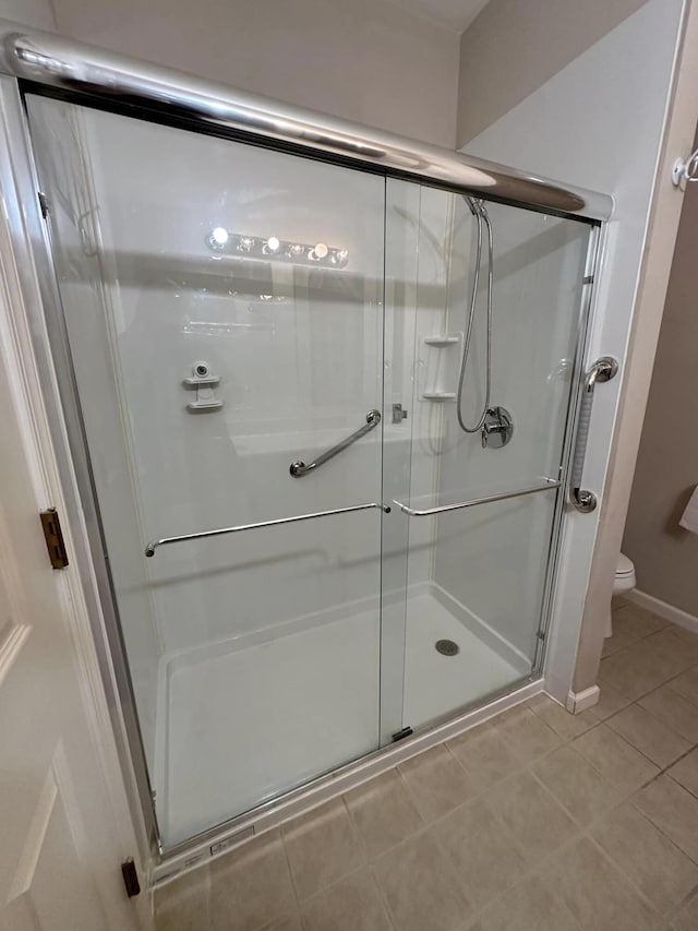 bathroom with tile patterned flooring, toilet, and an enclosed shower