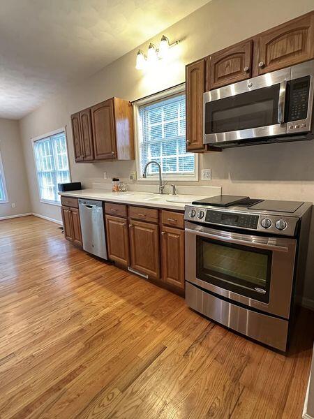 kitchen with appliances with stainless steel finishes, sink, and light hardwood / wood-style flooring