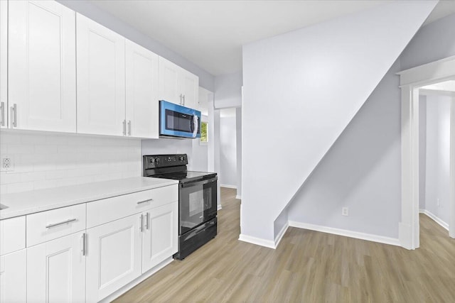 kitchen featuring light wood-type flooring, white cabinetry, black range with electric cooktop, and backsplash