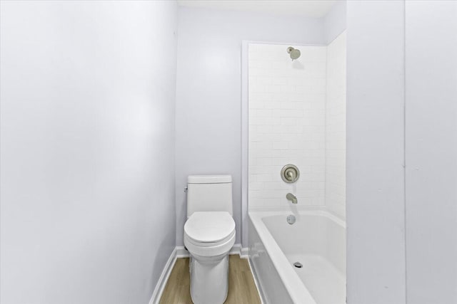 bathroom featuring wood-type flooring, tiled shower / bath combo, and toilet