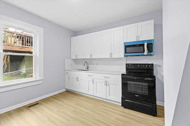 kitchen featuring black / electric stove, sink, light hardwood / wood-style floors, and white cabinetry