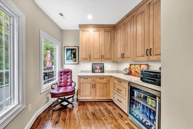 kitchen featuring wine cooler, a healthy amount of sunlight, light stone countertops, and dark hardwood / wood-style flooring