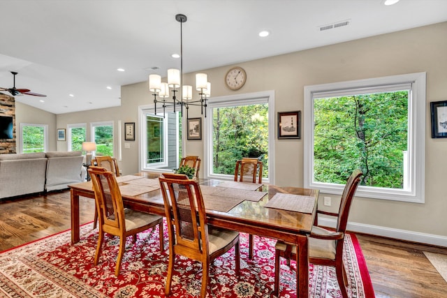 dining area with lofted ceiling, hardwood / wood-style floors, and ceiling fan with notable chandelier