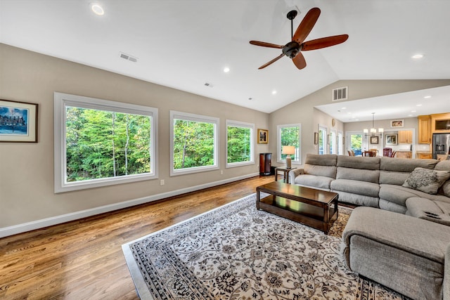 living room featuring a healthy amount of sunlight, lofted ceiling, light hardwood / wood-style flooring, and ceiling fan with notable chandelier