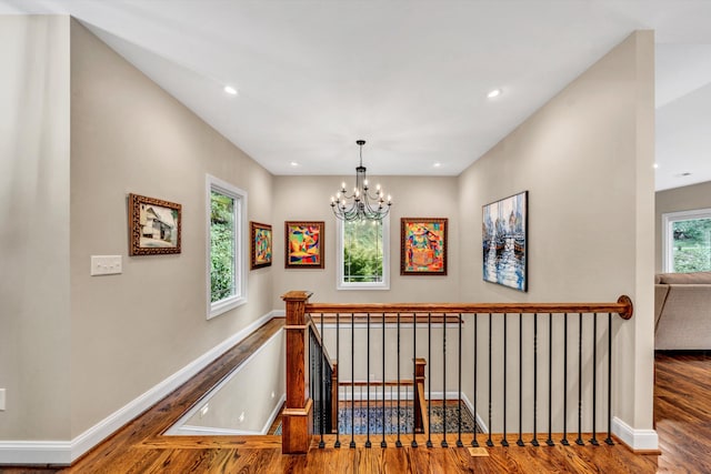 hallway with hardwood / wood-style flooring and an inviting chandelier