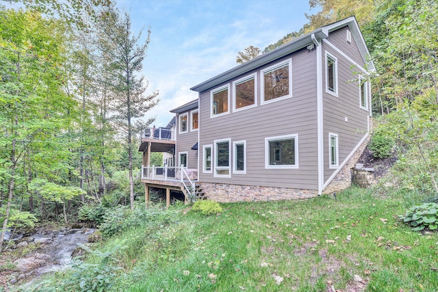 rear view of property featuring a yard and a wooden deck