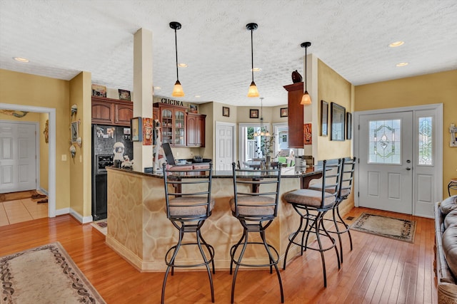 kitchen with a breakfast bar area, black refrigerator with ice dispenser, kitchen peninsula, and a healthy amount of sunlight