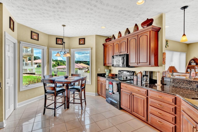 kitchen with light tile patterned floors, black appliances, a textured ceiling, and decorative light fixtures