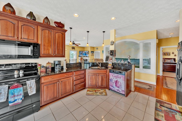 kitchen with pendant lighting, dark stone counters, a textured ceiling, sink, and black appliances