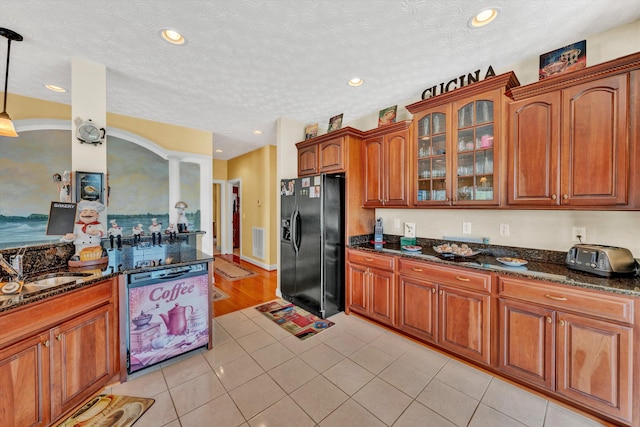 kitchen with dark stone counters, black fridge, decorative light fixtures, and dishwashing machine