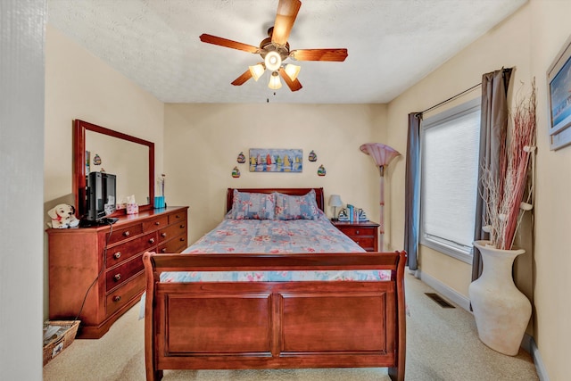 bedroom with light carpet, ceiling fan, and a textured ceiling