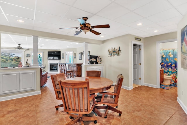 tiled dining space featuring ceiling fan and a drop ceiling