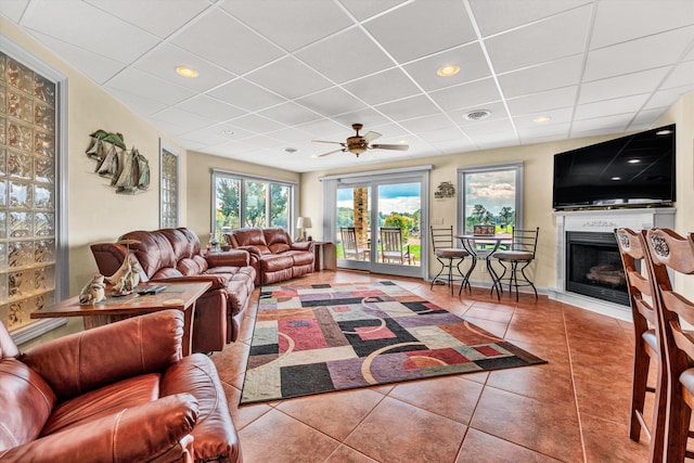 tiled living room featuring a drop ceiling and ceiling fan