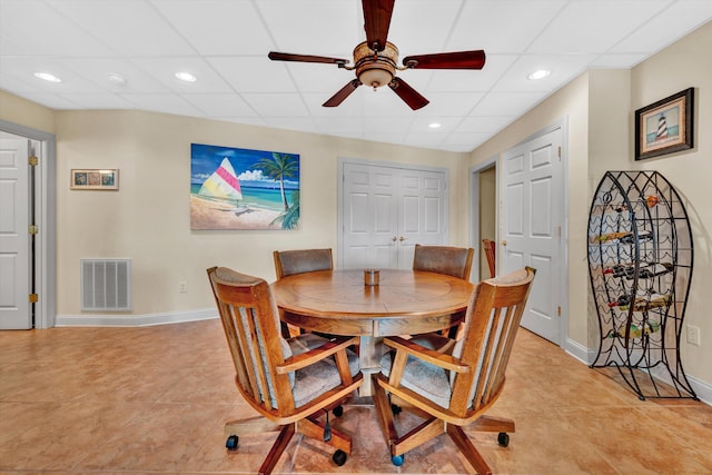 tiled dining area with a drop ceiling and ceiling fan