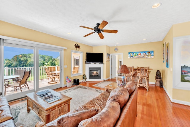 living room with light hardwood / wood-style flooring, ceiling fan, and a textured ceiling