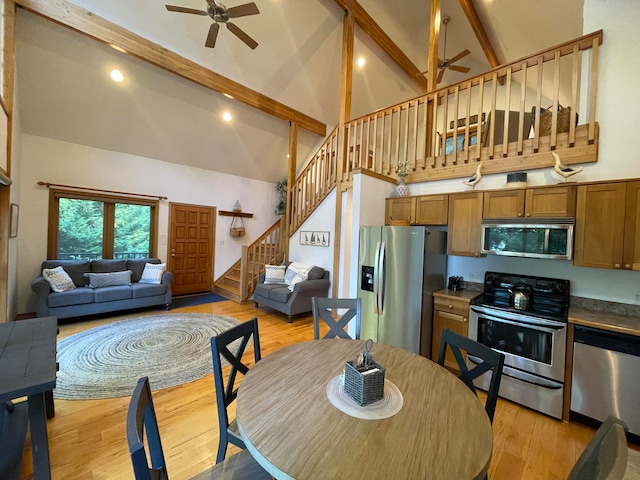 dining space featuring ceiling fan, beamed ceiling, light wood-type flooring, and high vaulted ceiling