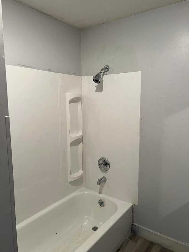 bathroom with washtub / shower combination and hardwood / wood-style flooring