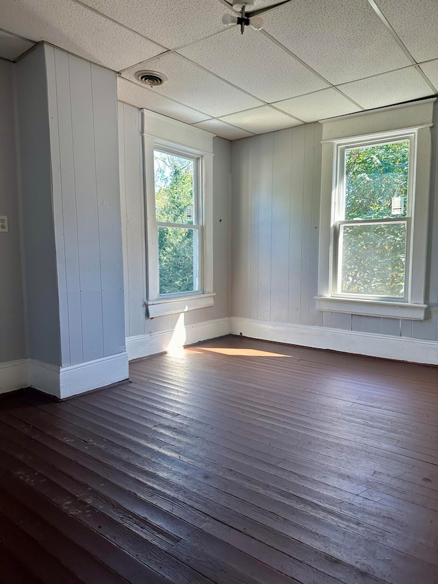 unfurnished room with a wealth of natural light, dark hardwood / wood-style floors, and a paneled ceiling