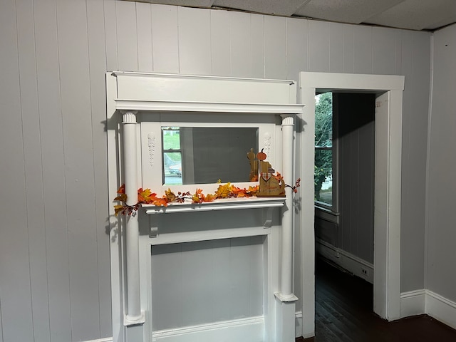 entryway with a drop ceiling, dark wood-type flooring, and wood walls