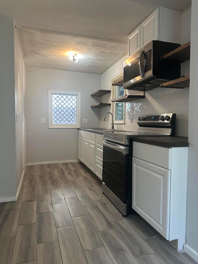 kitchen featuring appliances with stainless steel finishes, light wood-type flooring, a wealth of natural light, and white cabinets