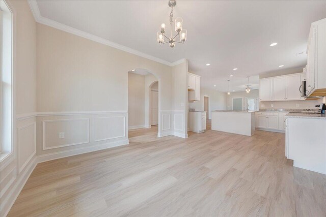 kitchen featuring pendant lighting, light hardwood / wood-style floors, white cabinetry, stainless steel appliances, and crown molding